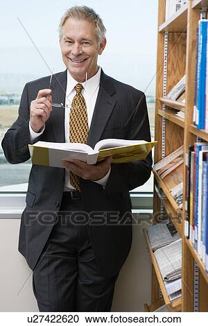 Businessman smiling in library, portrait View Large Photo Image Stock Image - Businessman smiling in library, portrait. Fotosearch