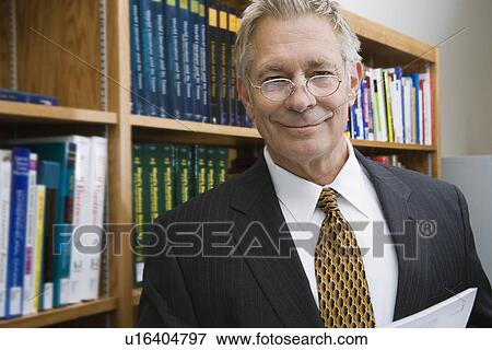Stock Photo - Businessman smiling in library, portrait. Fotosearch