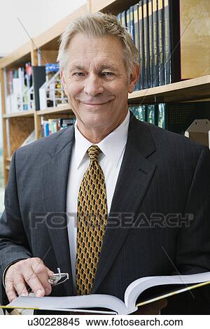 Businessman smiling in library, portrait View Large Photo Image Stock Photography - Businessman smiling in library, portrait. Fotosearch