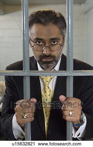 Businessman standing behind prison cell bars View Large Photo Image Stock Image - Businessman standing behind prison cell bars. Fotosearch