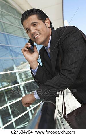 Businessman using mobile phone outside office building View Large Photo Image Picture - Businessman using mobile phone outside office building. Fotosearch