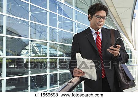 Businessman using mobile phone outside office building View Large Photo Image Stock Photo - Businessman using mobile phone outside office building. Fotosearch