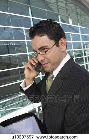 Businessman using mobile phone outside office building View Large Photo Image Stock Photo - Businessman using mobile phone outside office building. Fotosearch