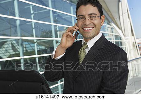 Businessman using mobile phone outside office building, portrait View Large Photo Image Stock Photo - Businessman using mobile phone outside office building, portrait. Fotosearch