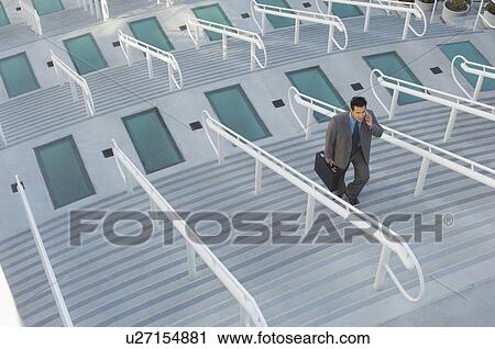 Stock Image - Businessman walking up stairs, elevated view. Fotosearch