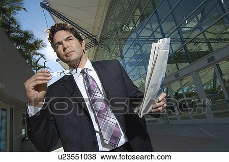 Stock Photo - Businessman with newspaper outside office building. Fotosearch