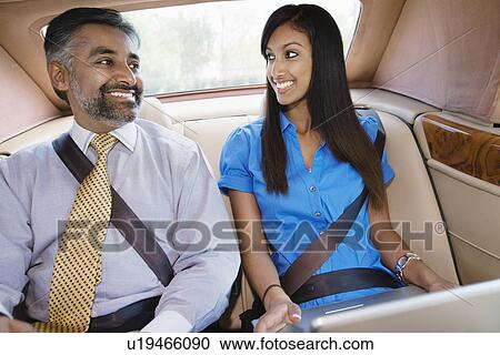Stock Image - Businesspeople Using Laptop in Car. Fotosearch
