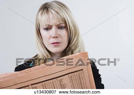 Stock Photo - Businesswoman Reading Stock Listings in Newspaper. Fotosearch
