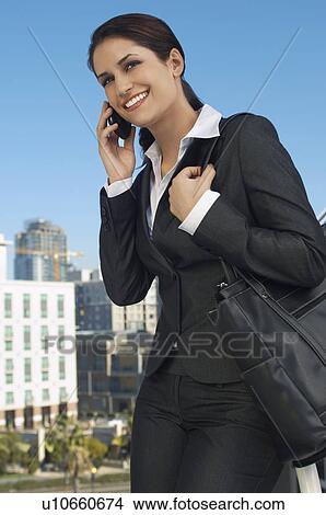 Picture - Businesswoman talking on mobile phone outdoors. Fotosearch