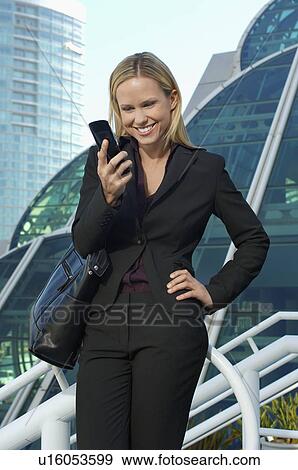 Businesswoman text messaging outside office building View Large Photo Image Stock Photo - Businesswoman text messaging outside office building. Fotosearch