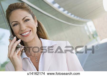 Businesswoman using cell phone on balcony, portrait View Large Photo Image Picture - Businesswoman using cell phone on balcony, portrait. Fotosearch
