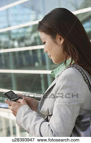 Businesswoman using mobile phone outside office building View Large Photo Image Stock Photo - Businesswoman using mobile phone outside office building. Fotosearch