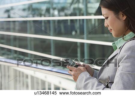 Businesswoman using mobile phone outside office building View Large Photo Image Stock Photography - Businesswoman using mobile phone outside office building. Fotosearch