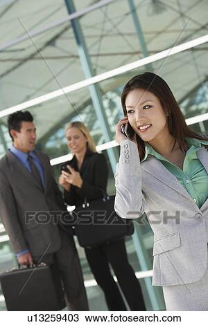 Businesswoman using mobile phone with colleagues in background, outdoors View Large Photo Image Stock Image - Businesswoman using mobile phone with colleagues in background, outdoors. Fotosearch