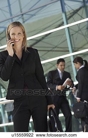 Businesswoman using mobile phone with coworkers in background View Large Photo Image Stock Image - Businesswoman using mobile phone with coworkers in background. Fotosearch