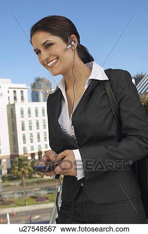 Stock Photo - Businesswoman wearing headset, text messaging, outdoors. Fotosearch
