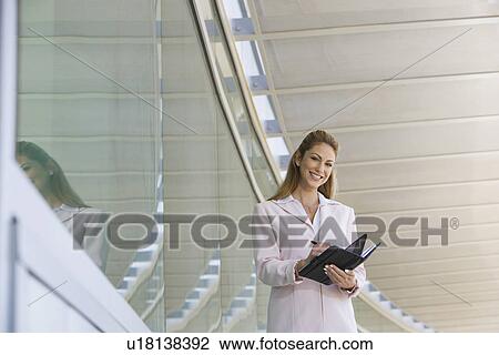 Stock Image - Businesswoman writing in planner outdoors, portrait. Fotosearch