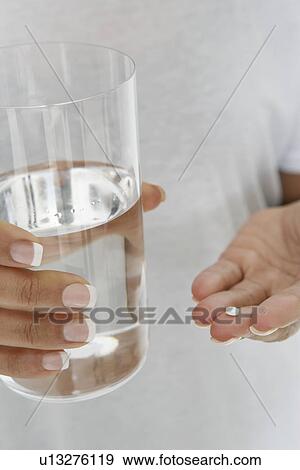 Close-up of woman's hands holding pill and glass of water View Large Photo Image Stock Photo - Close-up of woman's hands holding pill and glass of water. Fotosearch
