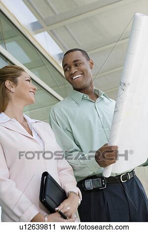 Stock Image - Colleagues looking at blueprints. Fotosearch