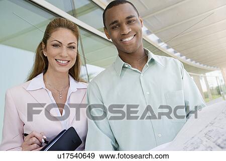 Stock Photo - Colleagues looking at blueprints. Fotosearch