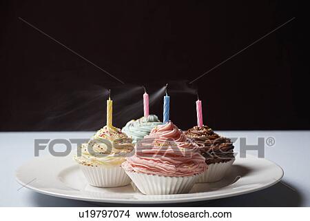 Picture - Colourful cupcakes with blowed birthday candles on plate. Fotosearch