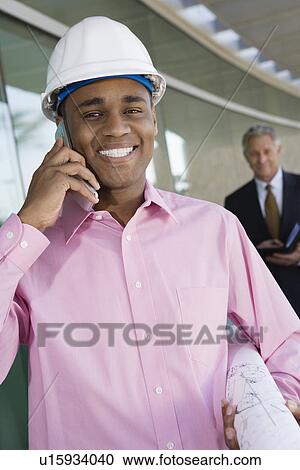 Construction worker using cell phone with businessman behind, portrait View Large Photo Image Stock Image - Construction worker using cell phone with businessman behind, portrait. Fotosearch