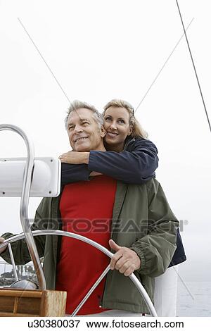 Couple at helm of sailboat, smiling View Large Photo Image Stock Photo - Couple at helm of sailboat, smiling. Fotosearch
