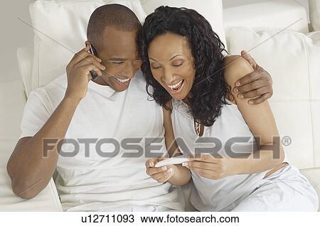 Couple examining pregnancy test in bed, man using mobile phone View Large Photo Image Stock Image - Couple examining pregnancy test in bed, man using mobile phone. Fotosearch
