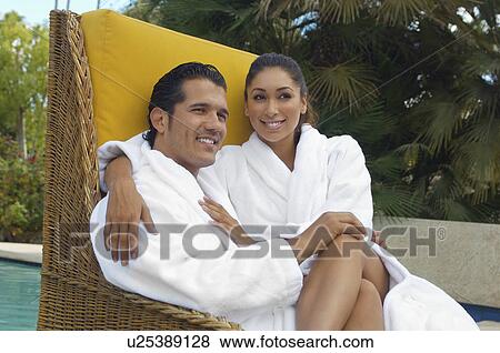Couple in bathrobes relaxing in wicker chair by pool View Large Photo Image Stock Photo - Couple in bathrobes relaxing in wicker chair by pool. Fotosearch