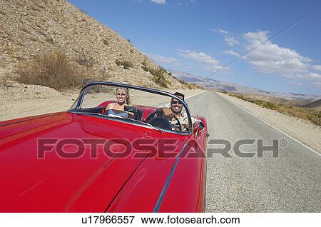 Stock Photo - Couple in classic car on desert road. Fotosearch