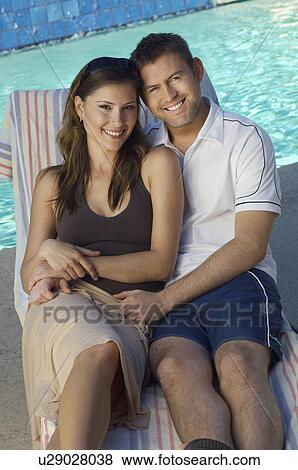 Couple in deck chair by swimming pool, portrait View Large Photo Image Stock Photo - Couple in deck chair by swimming pool, portrait. Fotosearch