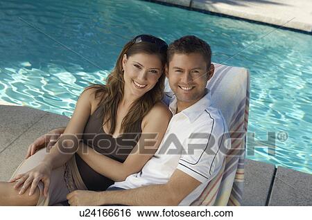 Couple in deck chair by swimming pool, portrait View Large Photo Image Stock Photograph - Couple in deck chair by swimming pool, portrait. Fotosearch