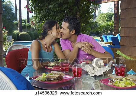 Couple kissing over meal on outdoor table View Large Photo Image Stock Photograph - Couple kissing over meal on outdoor table. Fotosearch