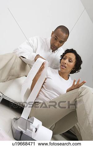 Stock Image - Couple Reading Adding Machine Tape. Fotosearch