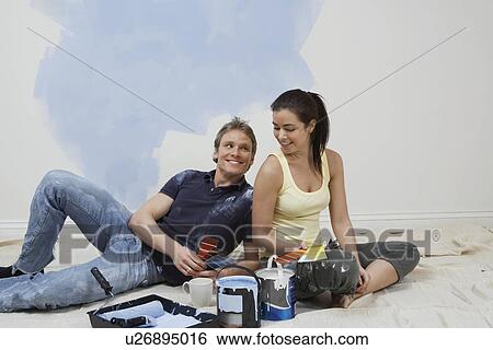 Stock Photograph - Couple resting by half-painted wall. Fotosearch