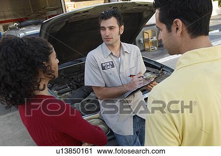 Couple talking to mechanic by open car hood View Large Photo Image Stock Image - Couple talking to mechanic by open car hood. Fotosearch