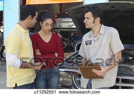 Couple talking to mechanic in front of open car hood View Large Photo Image Stock Image - Couple talking to mechanic in front of open car hood. Fotosearch