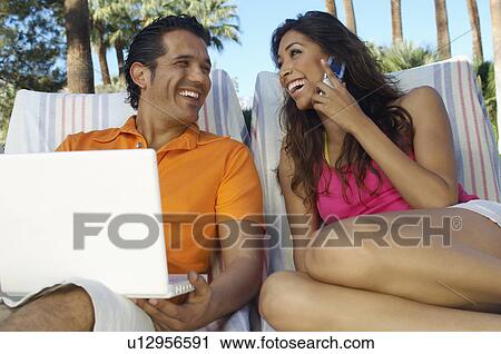 Couple with laptop and mobile phone relaxing in deckchairs View Large Photo Image Stock Image - Couple with laptop and mobile phone relaxing in deckchairs. Fotosearch