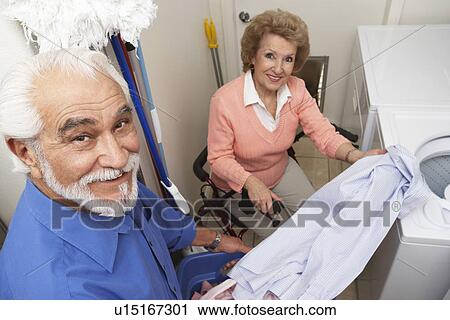 Stock Image - Couple with laundry by washing machine. Fotosearch