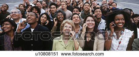 Stock Image - Crowd of people using mobile phones, outdoors. Fotosearch