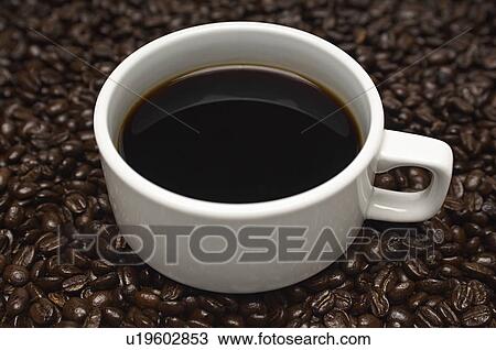 Stock Image - Cup of coffee on heap of coffee beans. Fotosearch