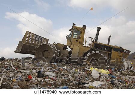 Stock Image - Digger working at landfill site. Fotosearch