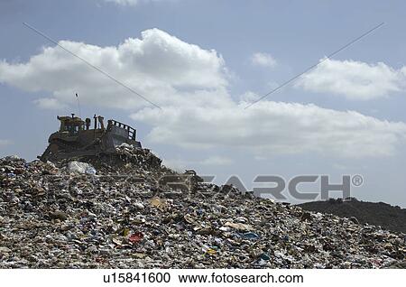 Stock Image - Digger working at landfill site. Fotosearch