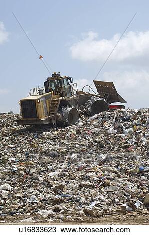 Stock Image - Digger working at landfill site. Fotosearch