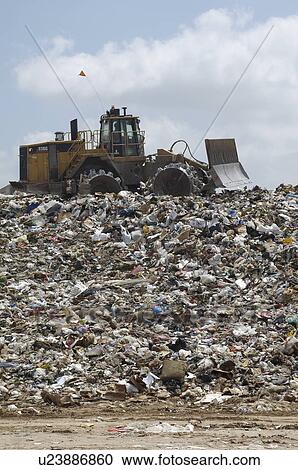 Stock Image - Digger working at landfill site. Fotosearch