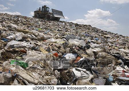 Stock Image - Digger working at landfill site. Fotosearch