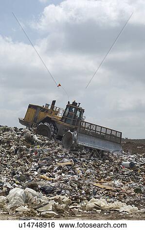 Digger working at landfill site View Large Photo Image Stock Photograph - Digger working at landfill site. Fotosearch