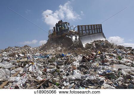 Stock Photograph - Digger working at landfill site. Fotosearch