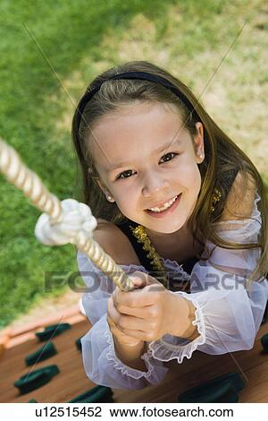 Stock Image - Dressed up Little Girl Climbing a Rope. Fotosearch
