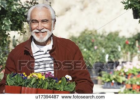 Stock Photo - Elderly man holding tray with potted flowers. Fotosearch